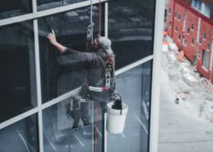 Operario en rappel trabajando sobre el ventanal de un edificio en altura